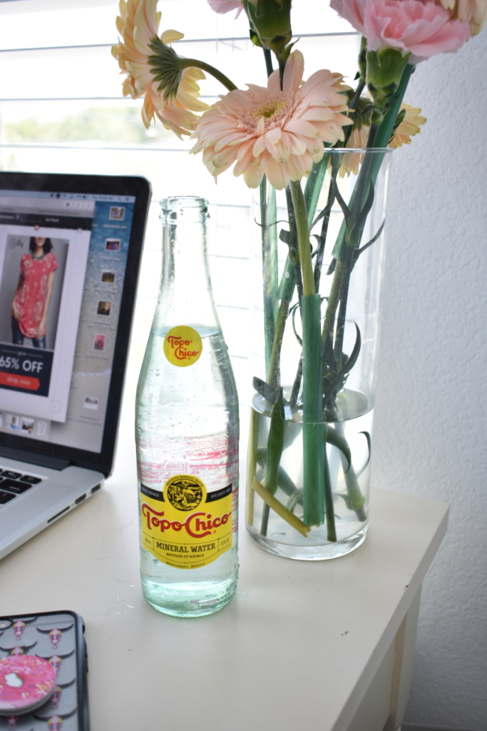 topo chico bottle vase with pink flowers cell phone and mac laptop